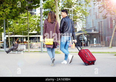 Les touristes Couple holding hands and walking dans la rue avec une valise de roue, Barcelone, Espagne Banque D'Images