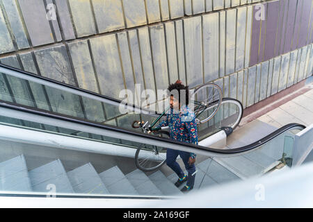 L'homme élégant transportant location sur Escalator Banque D'Images