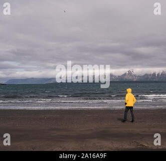 Matuer homme debout sur une plage à Eyjafjordurfjord, Islande, regardant la mer Banque D'Images