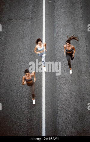 Vue du haut de trois jeunes femmes sportive s'exécutant sur une rue Banque D'Images