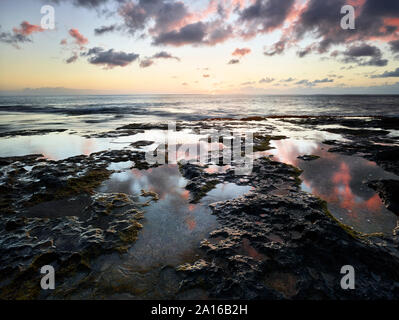 Vue panoramique sur mer contre ciel vu à partir de la plage rocheuse de Ka'ena Point State Park pendant le coucher du soleil Banque D'Images