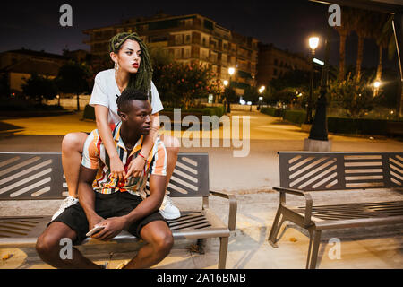 Cool jeune couple sur un banc dans la nuit dans la ville Banque D'Images