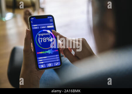 Jeune femme avec smartphone avec fonctions de contrôle smart home Banque D'Images