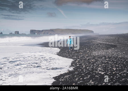 Jeune femme marche sur pieds nus sur une plage de lave en Islande Banque D'Images