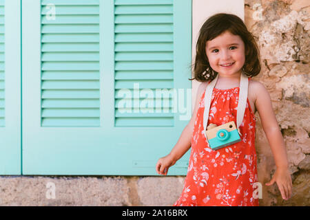 Portrait of happy little girl avec appareil photo jouet en bois Banque D'Images