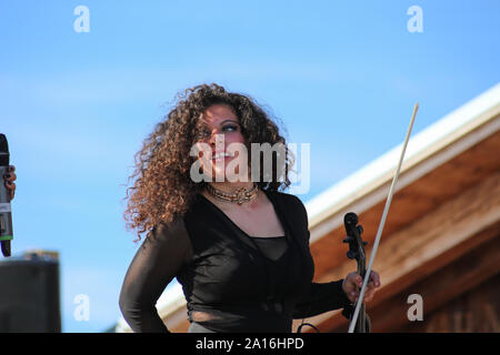 Violoniste femme travaillant dans un restaurant d'après-ski tenant son violon après son spectacle le jour ensoleillé. La Folie Douce Restaurant Saint Gervais De Chamonix. Banque D'Images