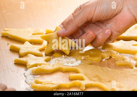 Mains de woman cutting cookies dans la pâte, gros plan Banque D'Images