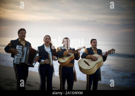 Avis de quatre musiciens jouant de leurs instruments sur une plage. Banque D'Images