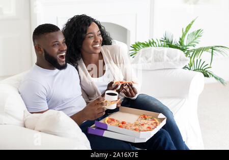 African American couple eating pizza et boire du café à la maison Banque D'Images