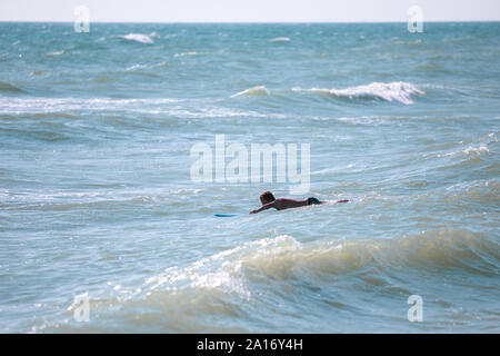 Man with surfboard nager dans la mer Banque D'Images
