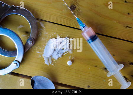 Indonésie rupiah et prêt pour la cocaïne utilise sur table en bois. Selective focus sur les menottes. La cocaïne des toxicomanies Concept Banque D'Images