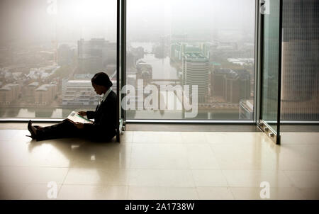 Young businesswoman sitting on floor tout en lisant un journal. Banque D'Images