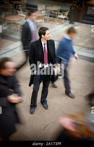 Les gens en passant devant un jeune homme d'affaires. Banque D'Images