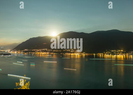 Bateau nautique déplacer de nuit des temps d'exposition sur le lac alpin avec vue sur la montagne et la Lune prends en Suisse. Banque D'Images