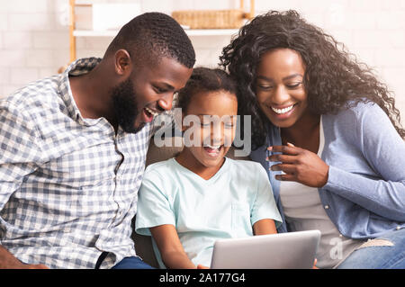 La famille noire regarder vidéos drôles sur digital tablet Banque D'Images