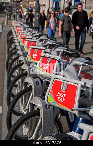 Les piétons à pied par une rangée de simplement manger des vélos de location sur Waverley Bridge, Edinburgh, Ecosse, Royaume-Uni. Banque D'Images