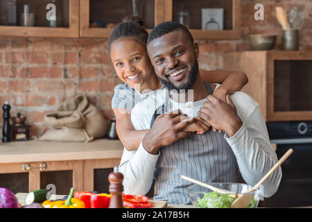 Reconnaissant petite fille embrassant son père avec amour dans la cuisine Banque D'Images