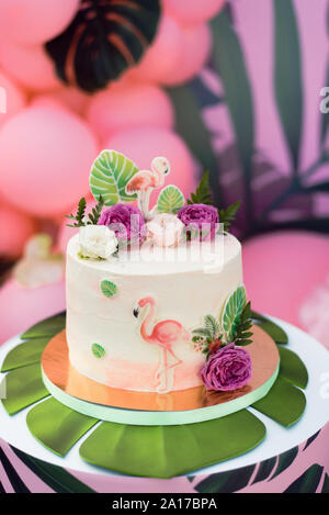 Gâteau rose avec des flamants roses pour la maison de vacances. Gâteau avec une variété de décors, feuilles de palmier et des fleurs fraîches Banque D'Images