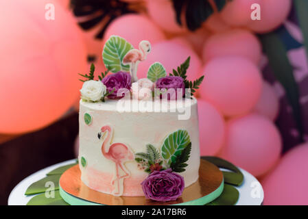 Gâteau rose avec des flamants roses pour la maison de vacances. Gâteau avec une variété de décors, feuilles de palmier et des fleurs fraîches Banque D'Images