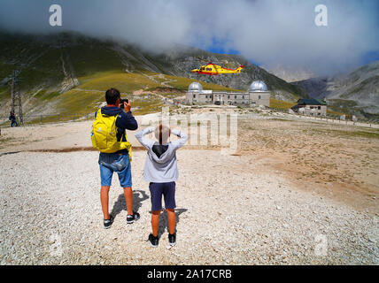 Les marcheurs regardez un hélicoptère d'urgence dégager de près de l'observatoire de Campo Imperatore dans le Gran Sasso, Abruzzo, Italie. Banque D'Images