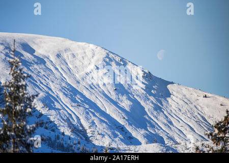 La crête de la montagne de neige devant la lune, dans les Carpates roumaines Banque D'Images