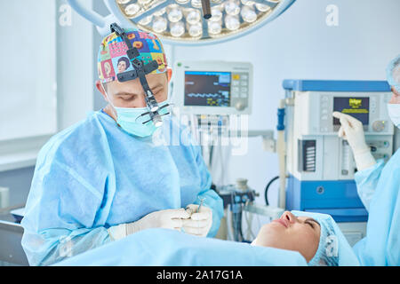 Plusieurs médecins entourant patient sur table d'opération pendant leur travail. Les chirurgiens de l'équipe au travail en salle d'opération. Banque D'Images