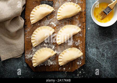 Tartes à la main ou avec des matières de remplissage pierogies de pommes de terre sur une planche prête à être cuite Banque D'Images