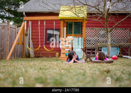 Deux enfants réside dans l'herbe en parlant de cour avec portique en arrière-plan Banque D'Images