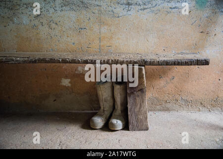 Des bottes en caoutchouc sous un banc en bois de la vieille maison de campagne Banque D'Images