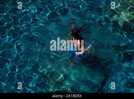 Jeune homme aux longues dreadlocks bénéficiant d'eau bleu clair beach Banque D'Images