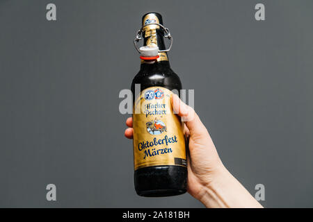 Muich, Allemagne - 3 Mar 2019 : Man hand holding boire bouteille de bière traditionnelle Marzen Comprimés Hacker Pschorr beer contre l'arrière-plan gris Banque D'Images