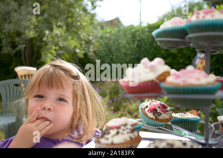 Jeune fille cupcakes dégustation Banque D'Images