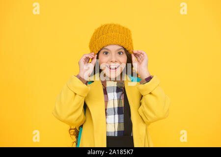 Bonnet hiver accessoire. Des cheveux longs de fille fond jaune. Saison froide concept. Accessoire de mode d'hiver. Petit enfant portant chapeau chaud. Choisissez entre plus mignonne et la plus branchée. Kid girl porter chapeau tricoté. Banque D'Images