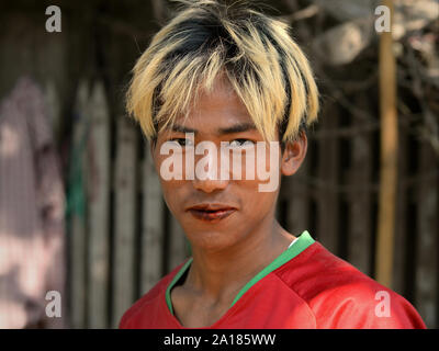 Jeune homme blond-birmane avec les cheveux teints en rouge, et les lèvres tachées de bétel bétel une mâche (feuille de bétel, d'arec, la chaux, les épices et le tabac). Banque D'Images