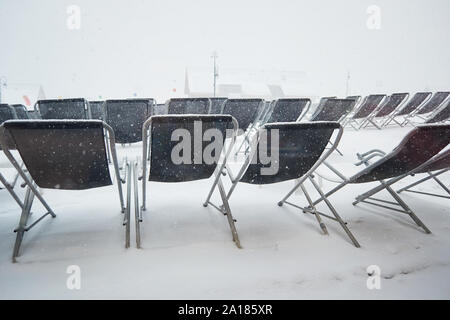 Transat vide des chaises sur une terrasse lors d'un blizzard de voile blanc d'hiver , Les Sybelles, France. Banque D'Images