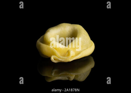 Un jaune frais entier rempli d'épinards tortelloni isolé sur verre noir Banque D'Images