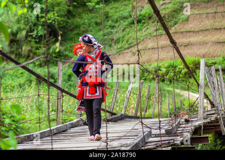 Minorité ethnique Dao rouge mère et bébé (DAO), sur un petit pont suspendu de l'Hoang Su Phi, Ha Giang province, dans le nord-ouest montagneux par Banque D'Images