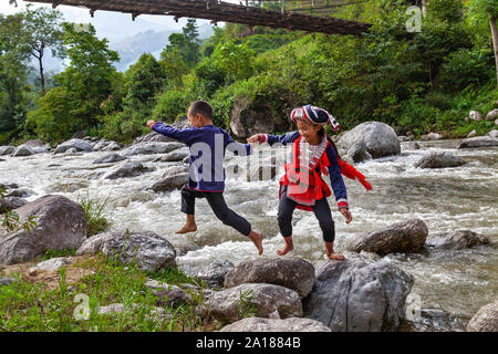 Minorité ethnique Dao rouge garçon et fille (DAO), la lecture par une rivière de Hoang Su Phi, Ha Giang province, dans la partie nord-ouest montagneux du Vietnam. Banque D'Images