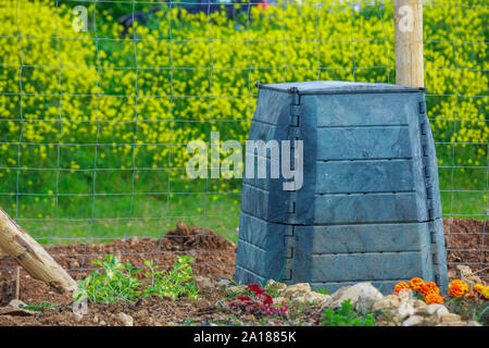 Bac à compost en plastique noir et petit chalet en bois dans le jardin de ville Banque D'Images