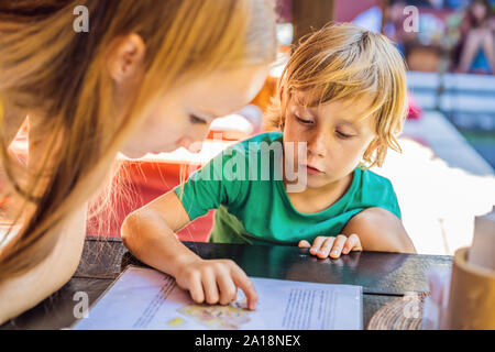 Mère avec son fils à la recherche au menu de restaurant Banque D'Images