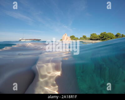 Closeup shot of woman's legs sous la mer avec petite île à l'horizon Banque D'Images