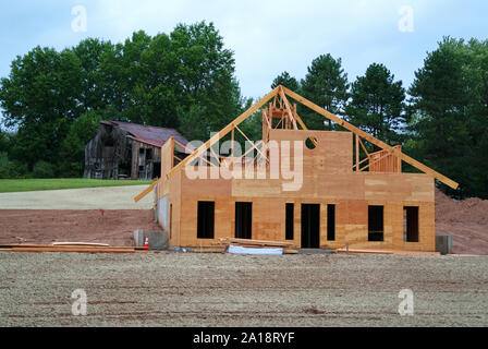 Une nouvelle maison ou à l'établissement d'être construit en face d'une vieille grange en train de s'effondrer. Symbolique de ce cycle de vie, et le passage du temps. Banque D'Images