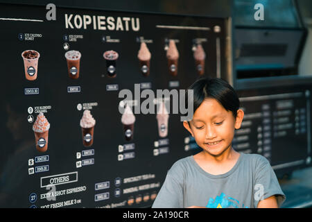 Putrajaya, Malaisie - septembre 6, 2019 : jeune garçon en attente de boissons au chocolat à l'Kopiesatu camion alimentaire vente de cafés. Banque D'Images