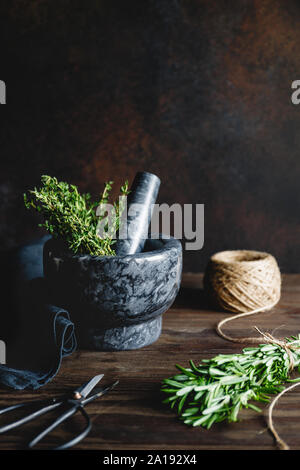 Des herbes fraîches dans un mortier de marbre sur une table. Style rustique de la photographie alimentaire. Banque D'Images