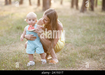 Jolie jeune femme - maman passe du temps activement avec son petit fils dans la nature. Le garçon n'est à l'âge de 10 mois. Avoir une belle journée d'été de la famille Banque D'Images