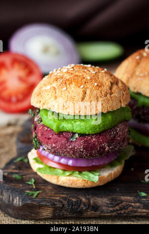 Deux burgers végétariens faits maison avec patty betterave, l'oignon, le concombre ou la sauce à l'avocat sur planche à découper en bois rustique Banque D'Images