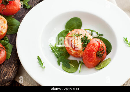 Tomates Grillées au parmesan, servi avec des feuilles d'épinards et de roquette. L'alimentation d'été Banque D'Images