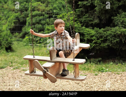 Un enfant de 5 ans enfant volant sur un plan en bois swing dans le parc d'été Banque D'Images