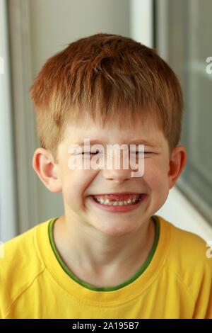 Close up portrait of a Boy in a yellow T-shirt vissant les yeux dont le haut avant les dents de lait sont tombés Banque D'Images