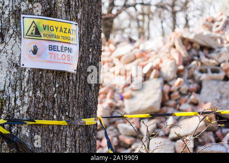 Panneau d'avertissement clouée sur un arbre dans la forêt : Danger, Démolition en cours. N'entrez pas. Muck, montagnes Sopron, Sopron, Hongrie. Banque D'Images